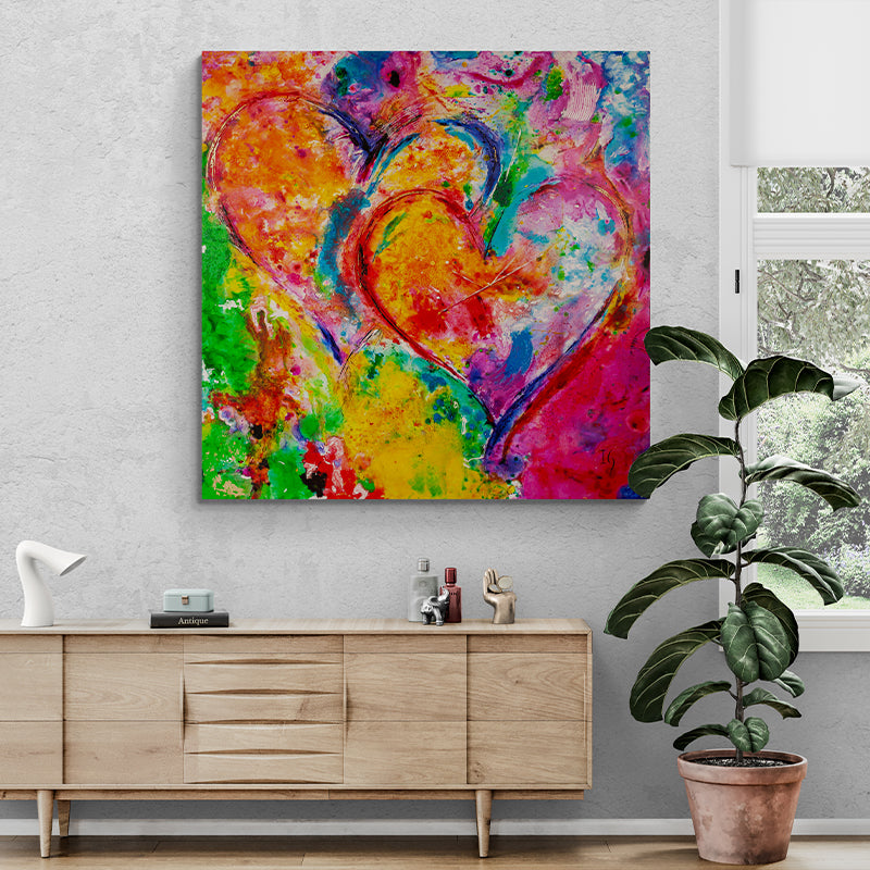 Passionate Symphony – Vibrant abstract heart painting in red, yellow, blue, and green, showcased in a contemporary space with a wooden sideboard, decorative accents, and natural light. A striking statement piece full of energy and emotion.