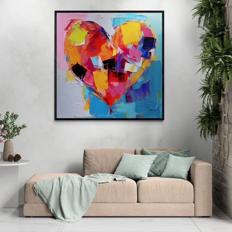 Abstract heart painting in bold colors hanging above a beige sofa, adding a vibrant touch to a cozy living room setting.